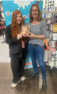 Autorin Doris Cornils mit Buchbloggerin Claudia. Beide halten gemeinsam das Buch "Stärken stärken mit Pferdestärken" in den Händen und lächeln in die Kamera.